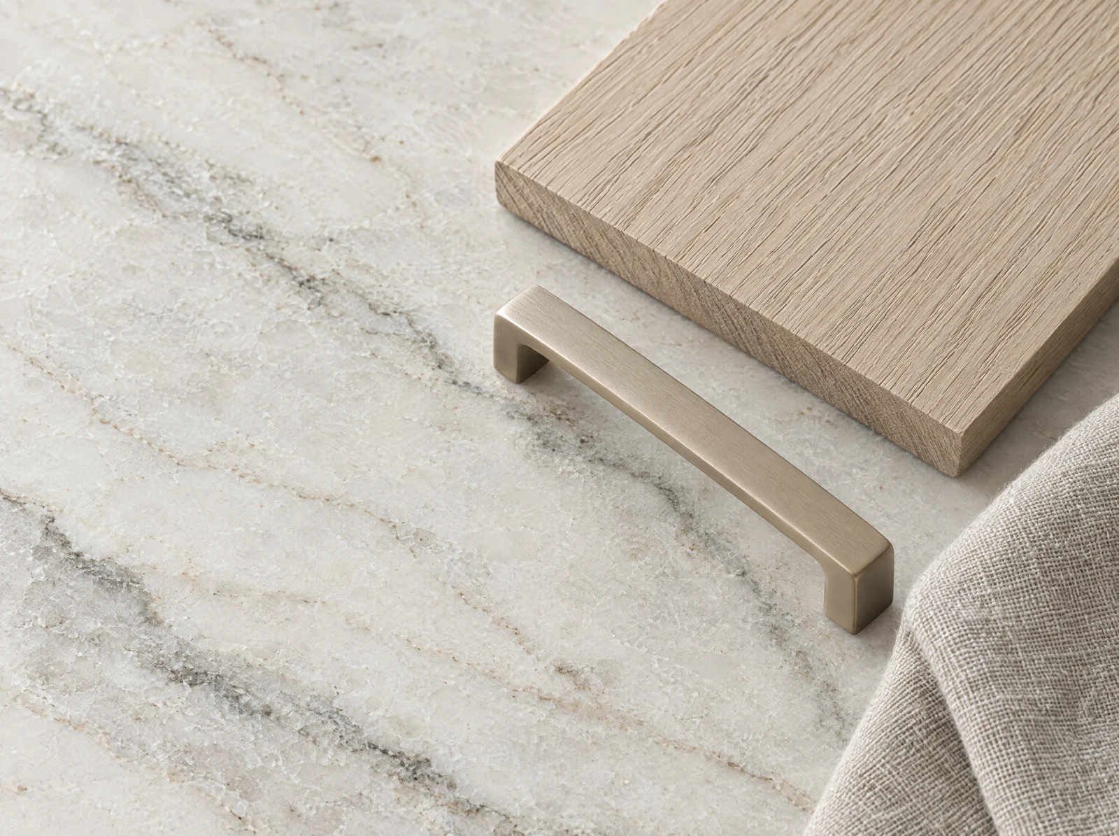 Honed pale stone, an oak sample, a brushed champagne handle and natural linen.